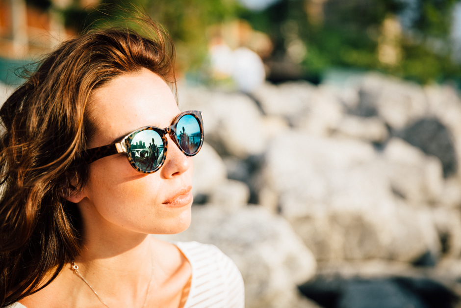 Akvile mit Sonnenbrille an der steinigen Ufermauer - Bild 1